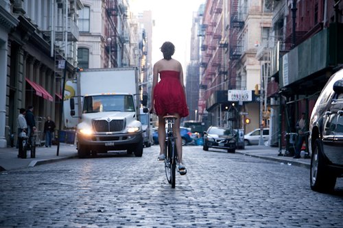 Una ragazza in bici vestita di rosso